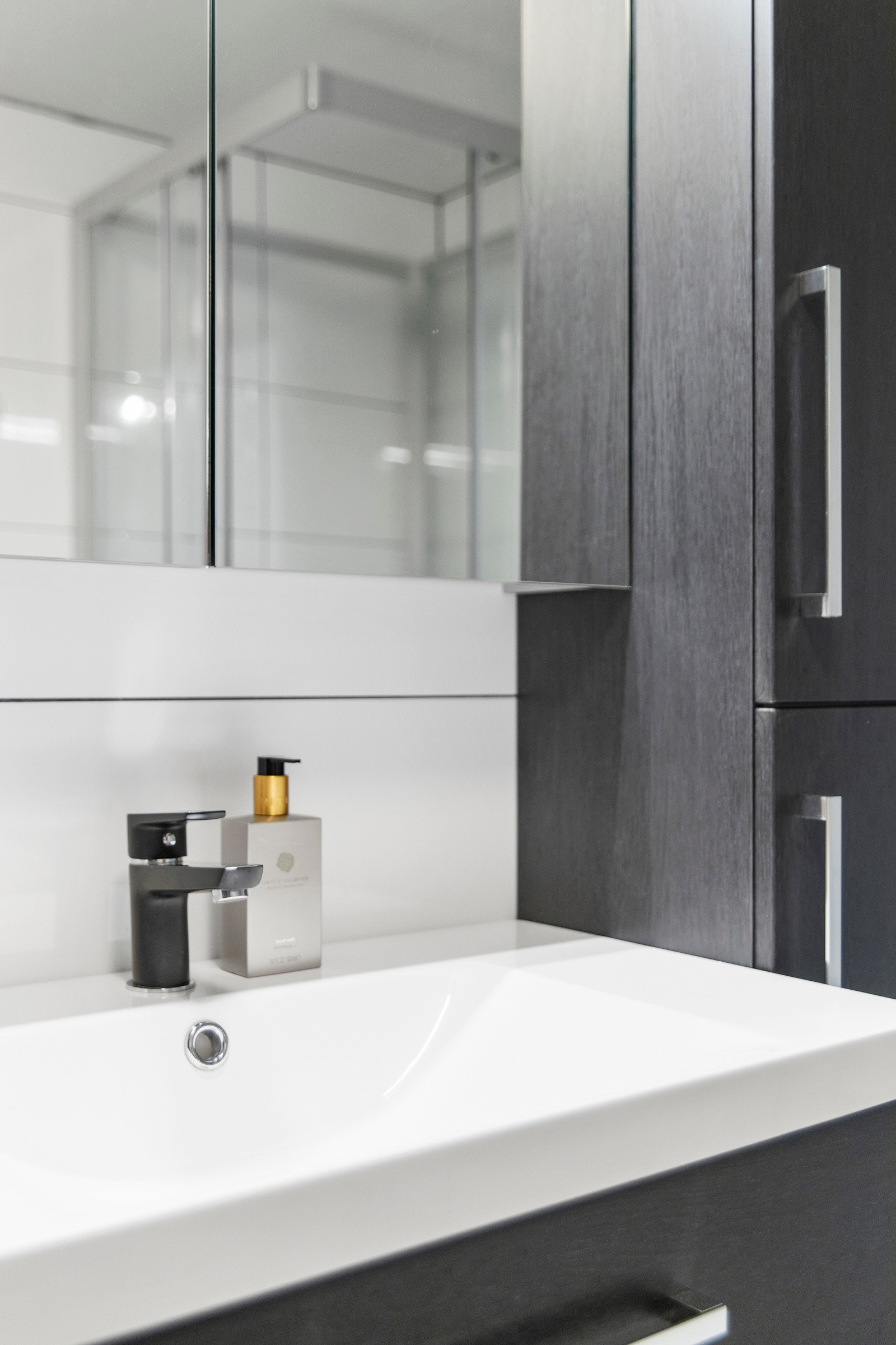 Servant over skuffeseksjon, høyskap og speilskap med belysning. Galleribilde