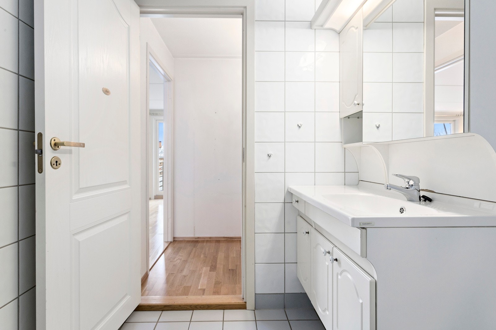 Badet er bygget opp med dusjsone med skyvedører av glass, innredning med ovenpåliggende servant, speilskap og opplegg for vaskemaskin Galleribilde