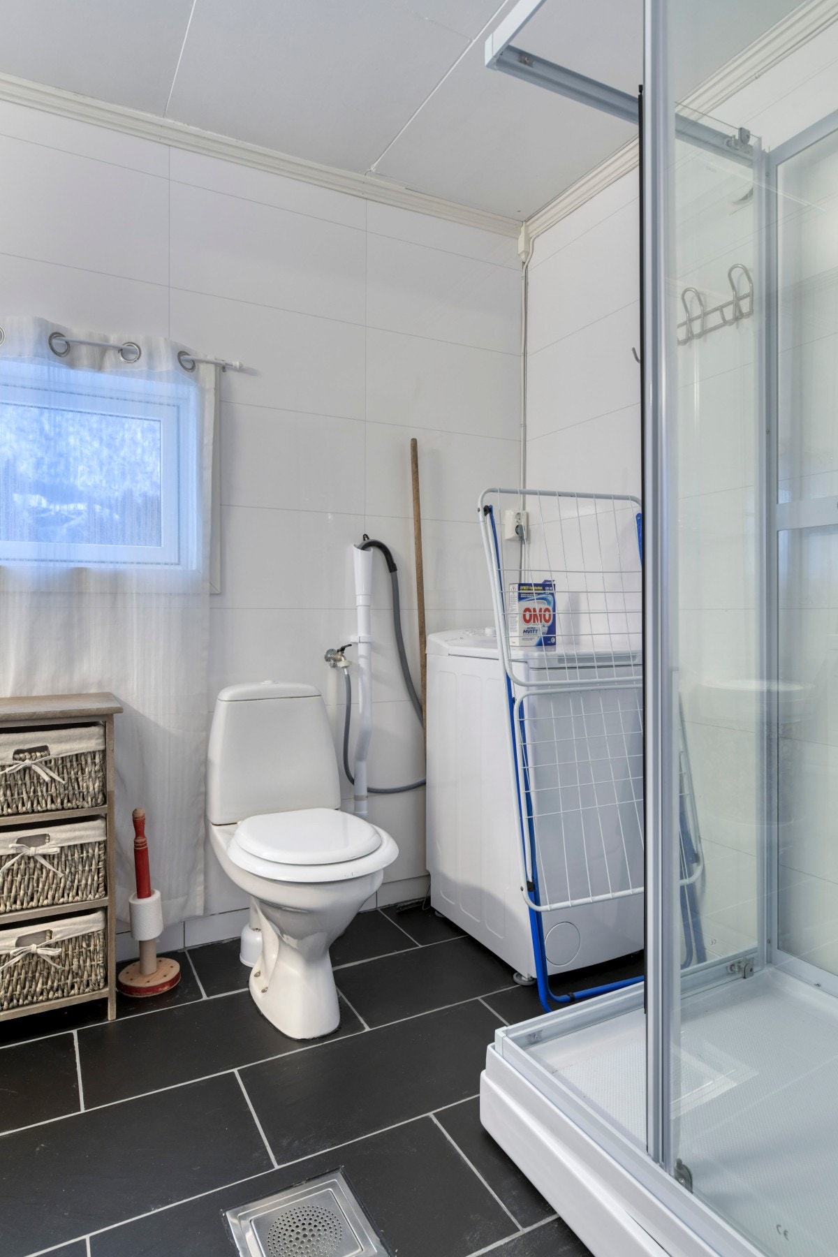 Badet har dusjkabinett, gulvmontert toalett, servant og opplegg for vaskemaskin Galleribilde