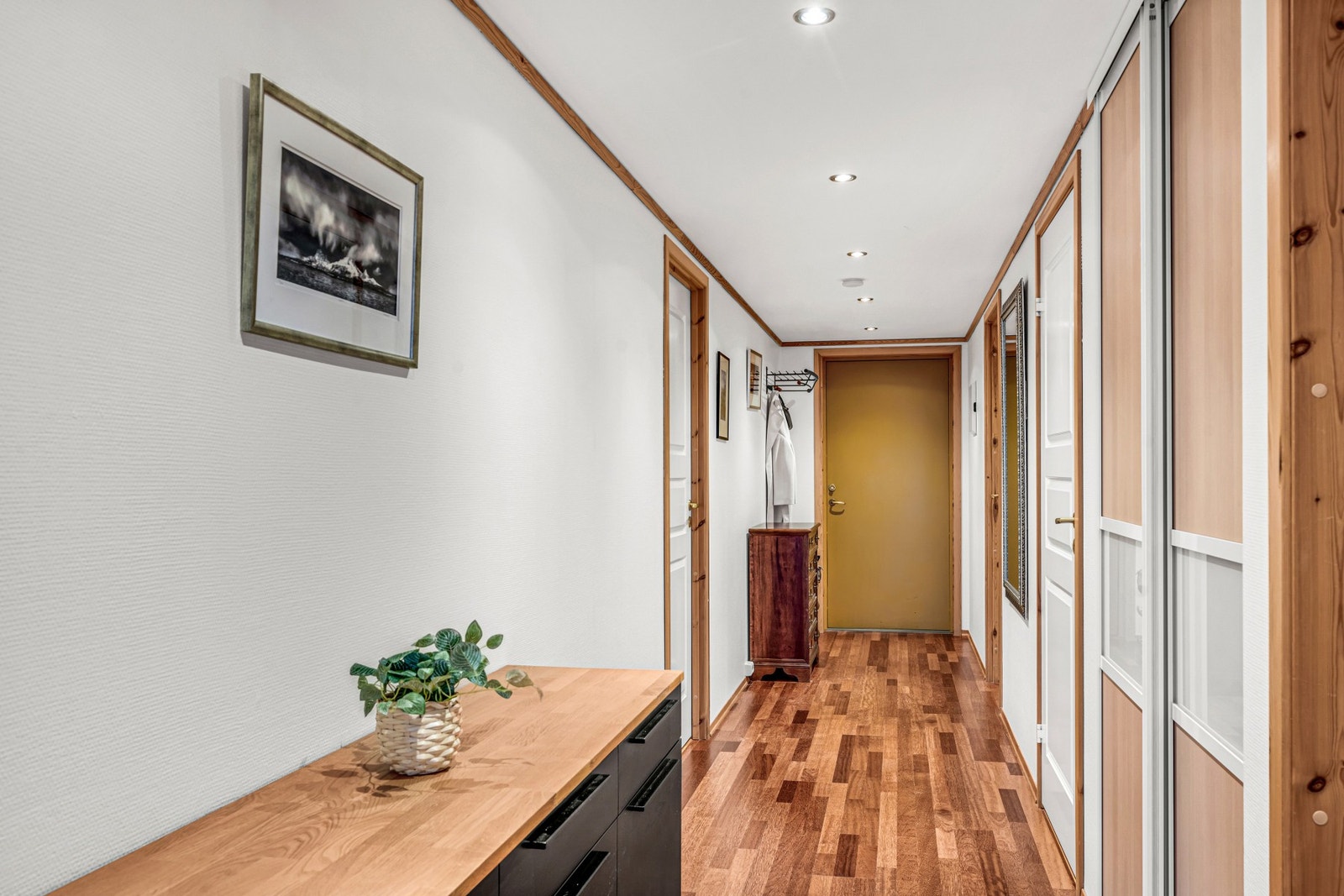 Gang sett mot inngangsdøren. Her har man dører inn til begge soverommene, badet og innendørs bod. Skyvedørsgarderobe med oppbevaringsplass i gangen + på begge soverommene. Galleribilde