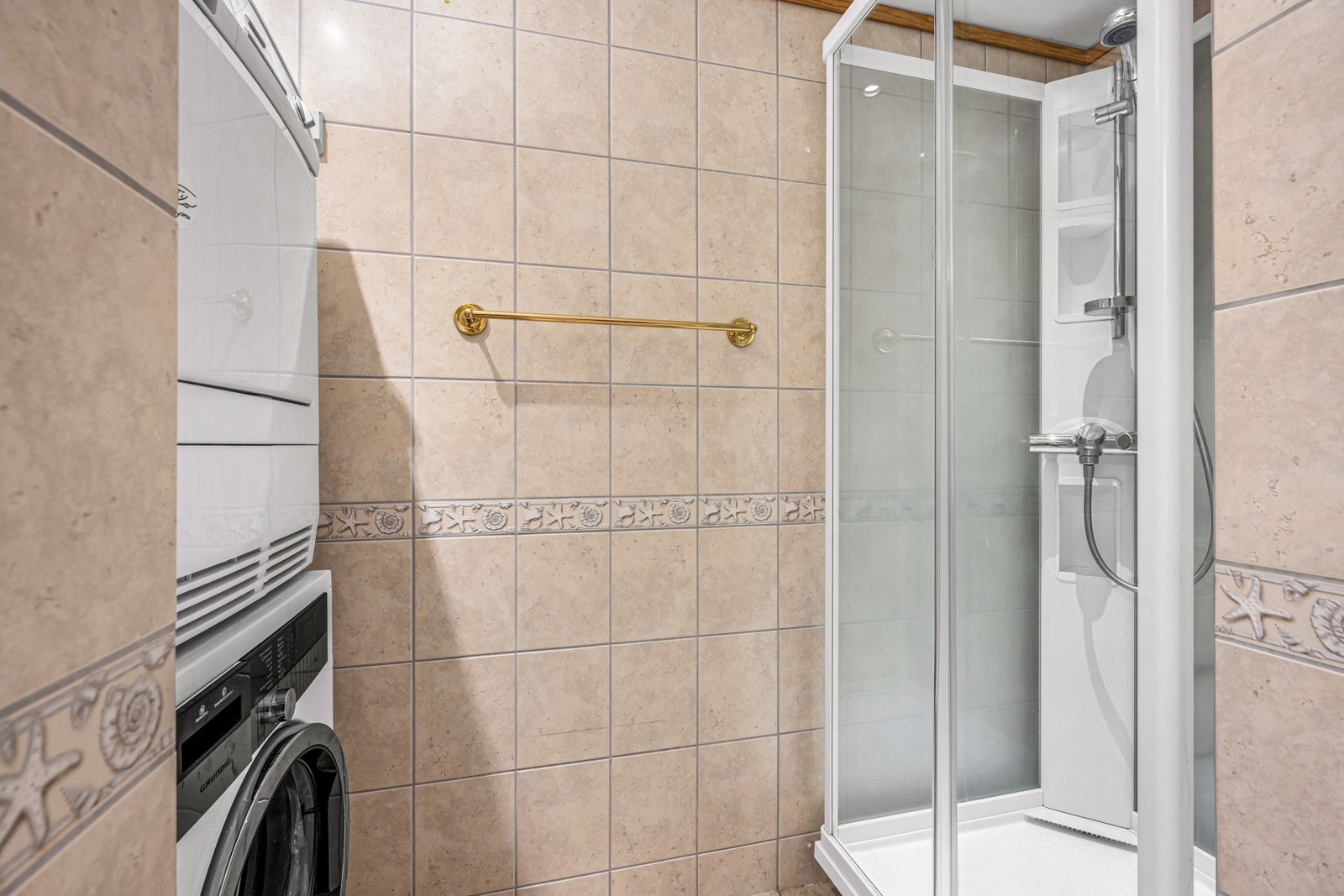 Dusjkabinett og opplegg for vaskemaskin er noe mer adskilt fra resten av badet bak skillevegger. Galleribilde