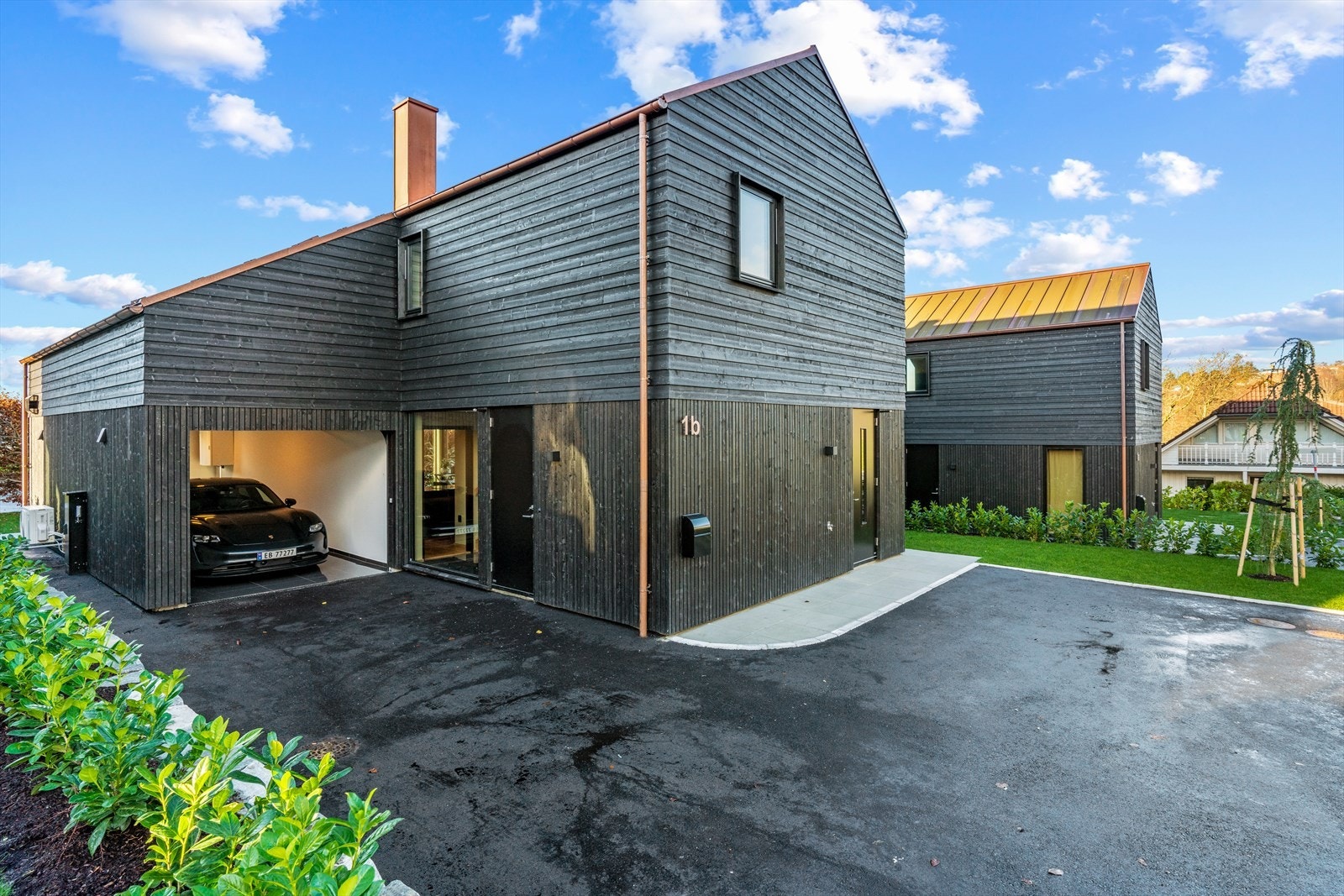 Strøken enebolig med svart kledning. Pipe, tak og renner i kobber Galleribilde