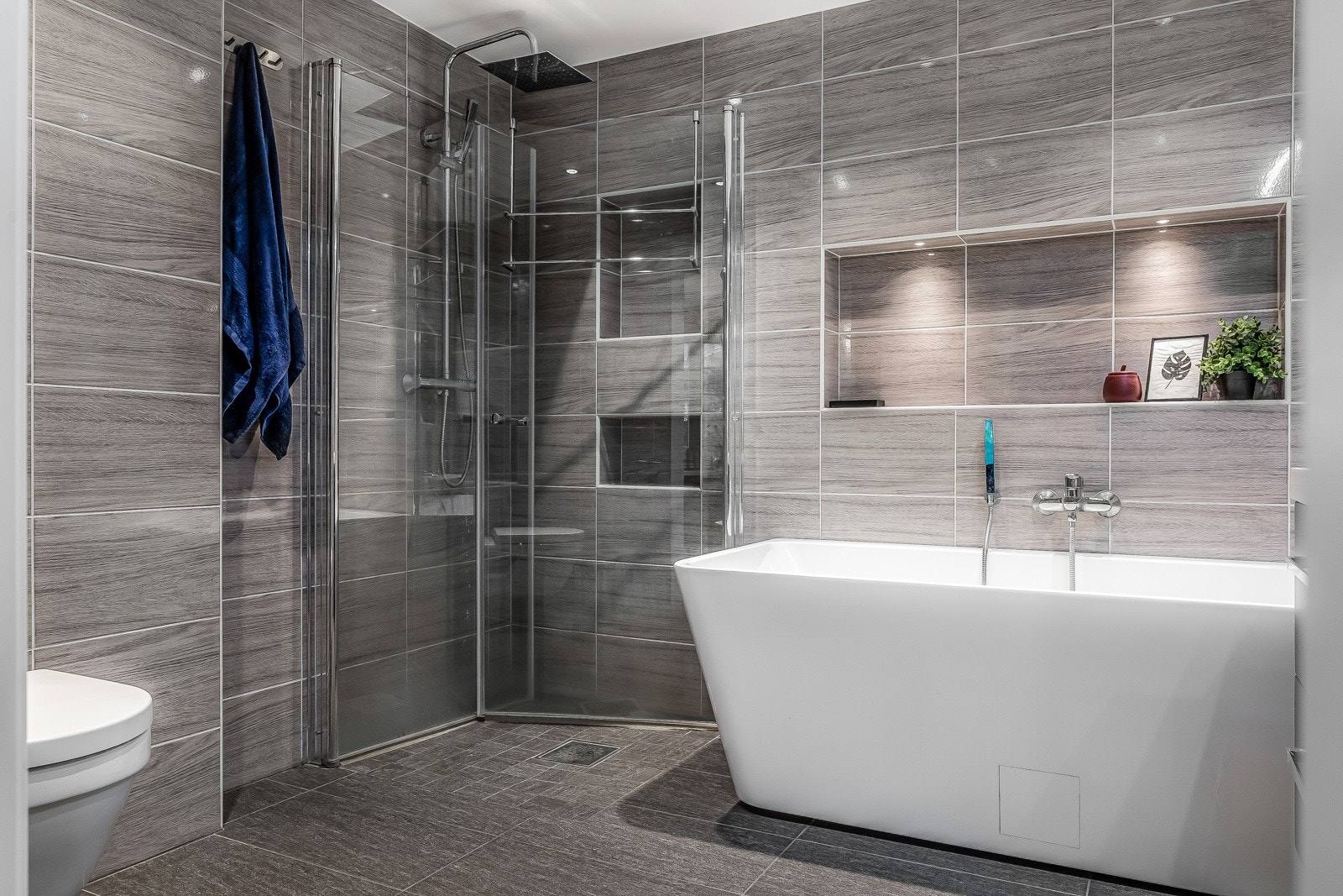 Bad 1. Badet har dusjhjørne med glassdører, frittstående badekar, vegghengt toalett og servantskap. Galleribilde