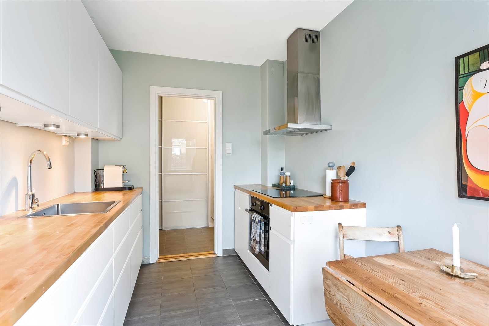 Pent kjøkken med glatte fronter og heltre benkeplate. Galleribilde