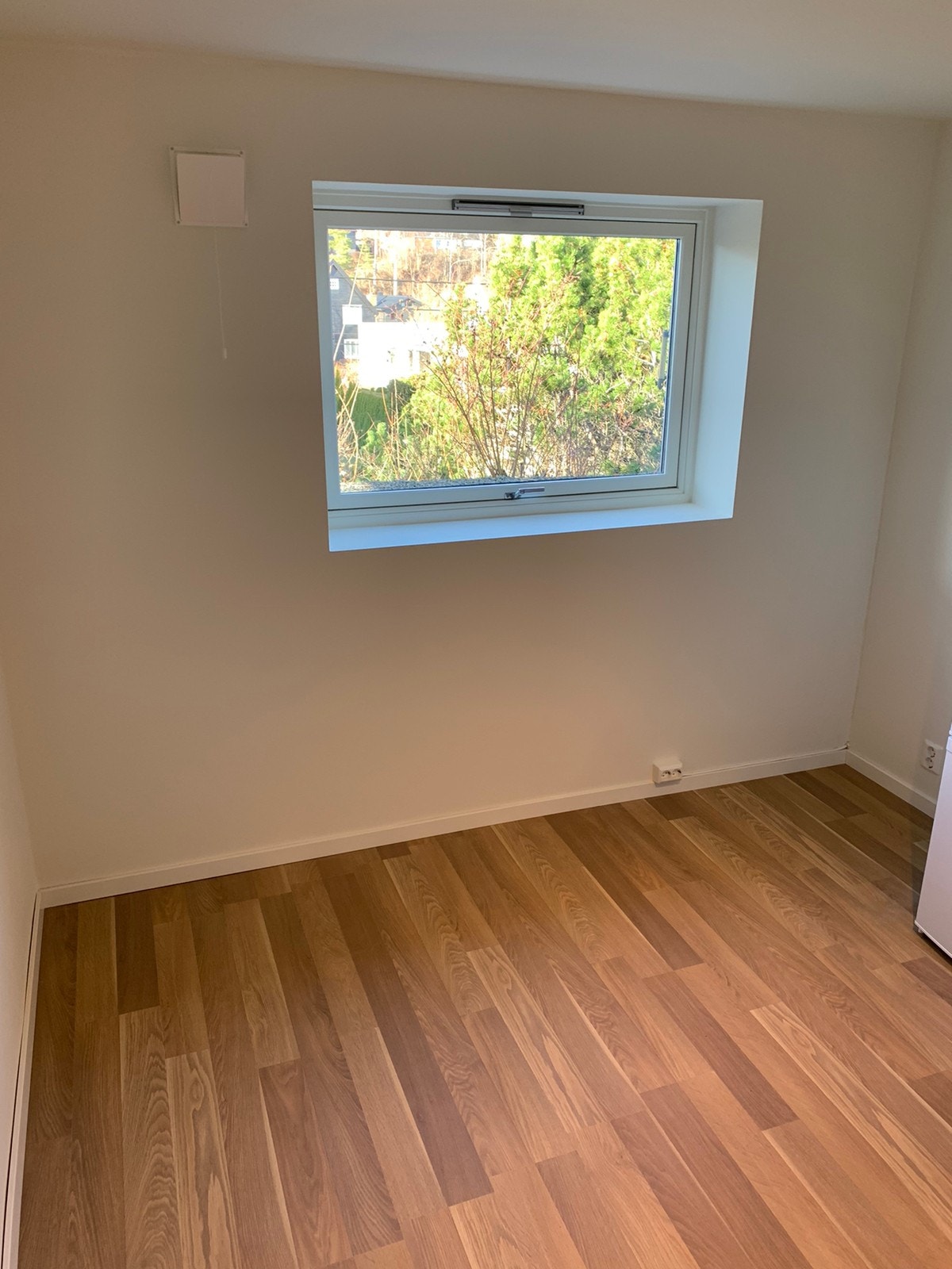 Stue med åpen kjøkkenløsning. Stort vindu med utsyn over området. Trær som er vist på bildet er nå fjernet, og det er plantet nytt for skjerming. Galleribilde