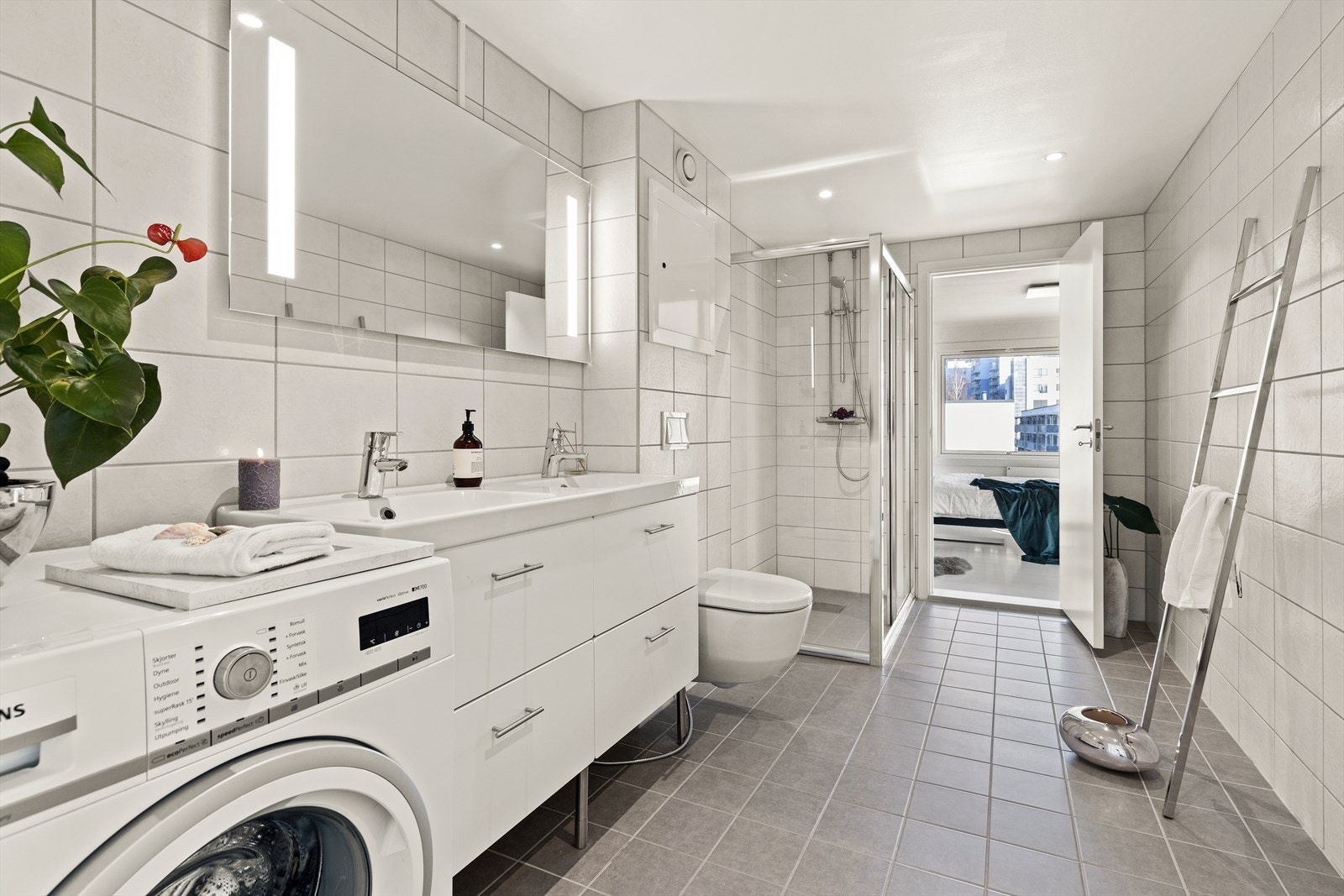 Delikat og stort baderom som ble oppgradert i regi av borettslaget i 2018. Fliser på gulv med gulvvarme og fliser på vegg. Dusjhjørne med dusjvegger i herdet glass, veggmontert WC og helstøpt dobbeltservant med servantskap. Galleribilde