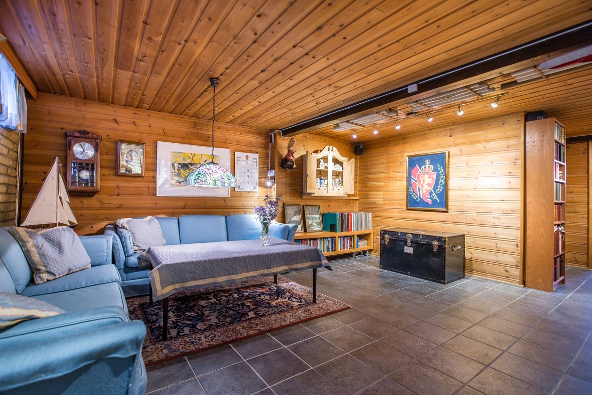 Fliser på gulv samt peis med innsats for vedfyring i kjeller. Galleribilde