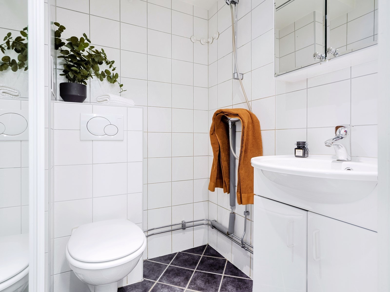 Baderom med vegghengt toalett, servant med underskap og dusjhjørne. Galleribilde