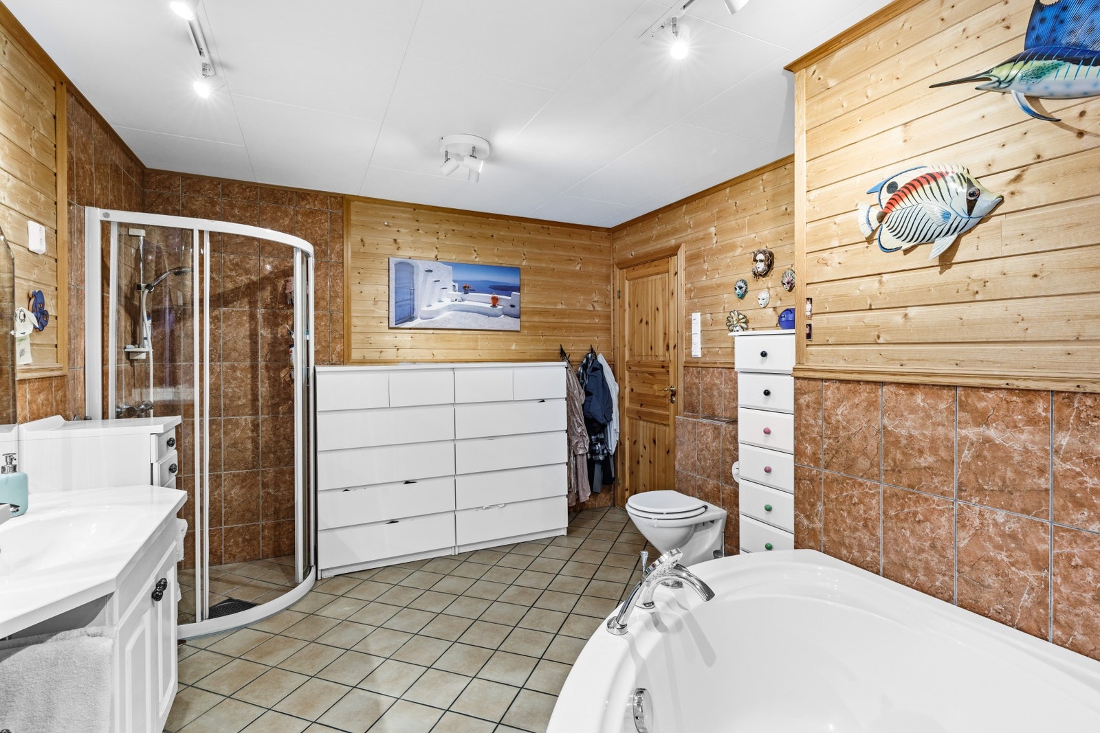 Baderom utstyrt med dusjhjørne, badekar, baderomsinnredning, skyllekum og opplegg for vaskemaskin Galleribilde