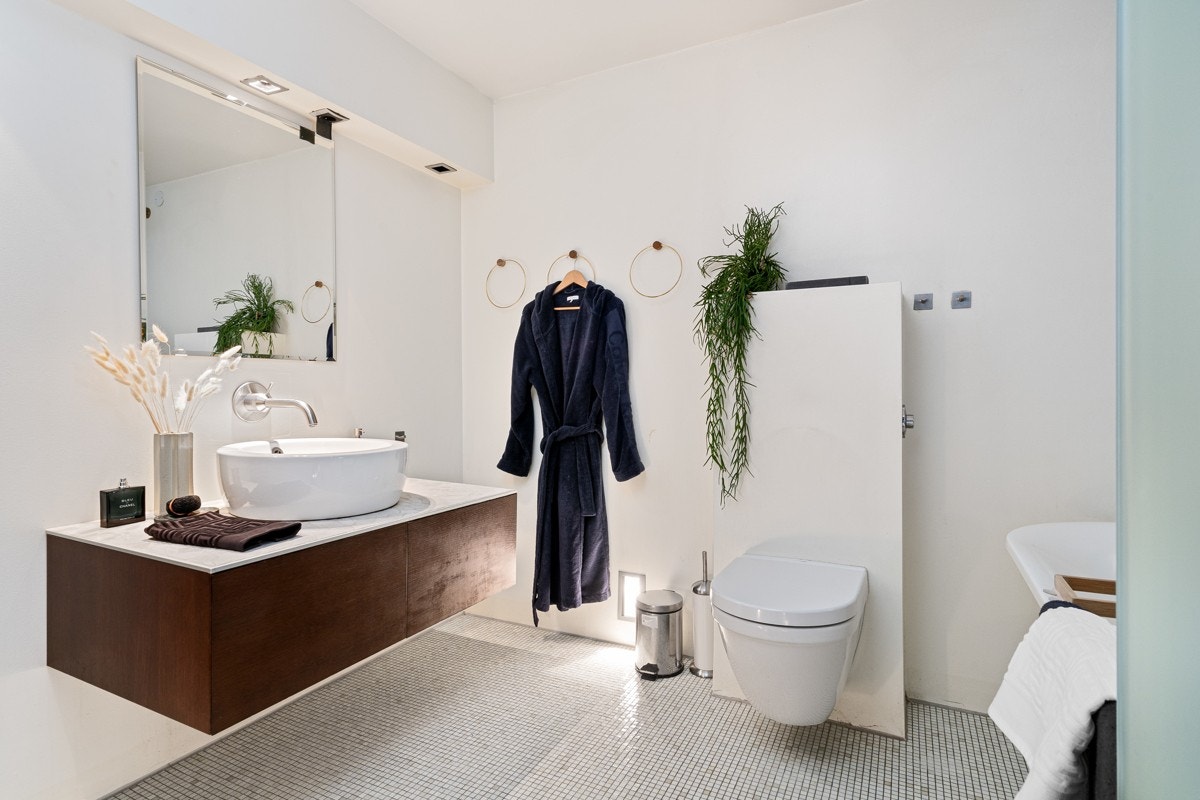 Stort og rålekkert baderom med mosaikkfliser på gulv, malte vegger og glassvegg rundt badekar Galleribilde