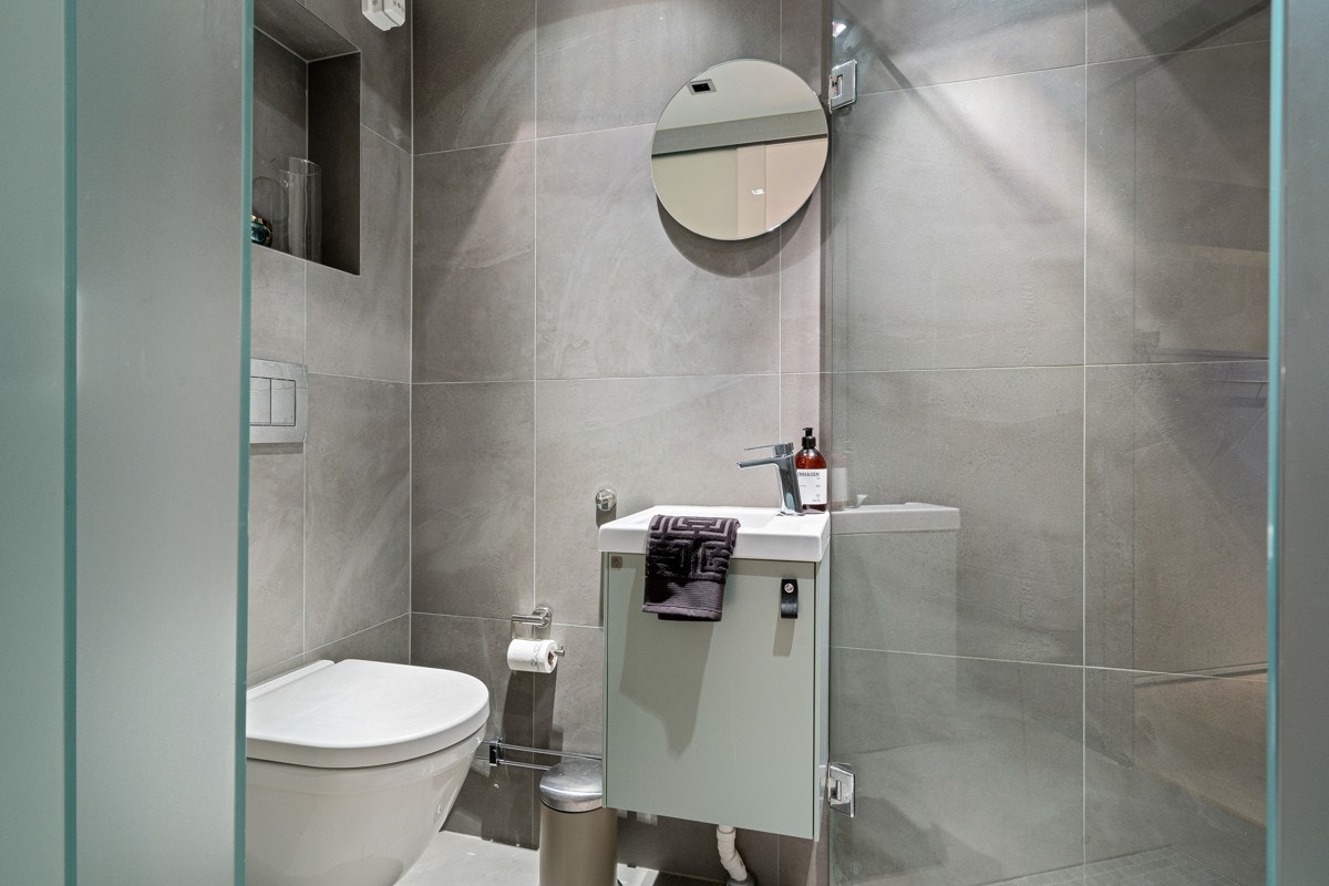 Pent og praktisk baderom i 1.etasje med flislagt gulv og nedsenket gulv i dusjnisje. Galleribilde