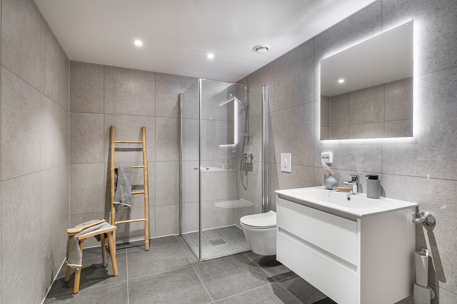 Grå fliser av storformat på gulv og vegger gir badet et helhetlig uttrykk. Galleribilde