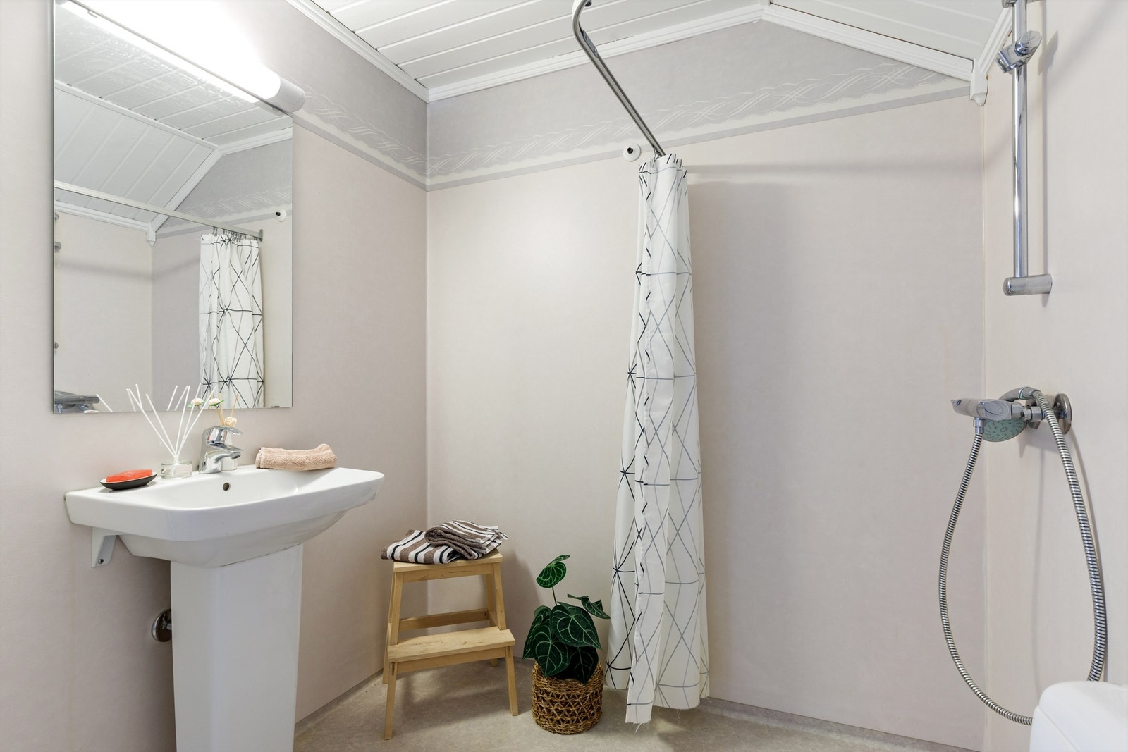 Bad i loftetasje med belegg på gulv og våtromstapet på vegger.
På badet er det wc, dusj og søyleservant. Galleribilde