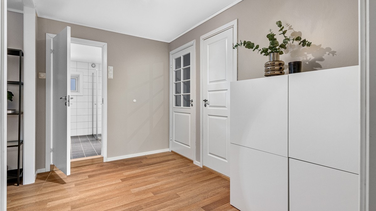 Innvendig gir entreen et godt førsteinntrykk av leiligheten og har blant annet laminatgulv, som er delikat kombinert med varme beige tonen på veggene som gir en lun og innbydende velkomst Galleribilde