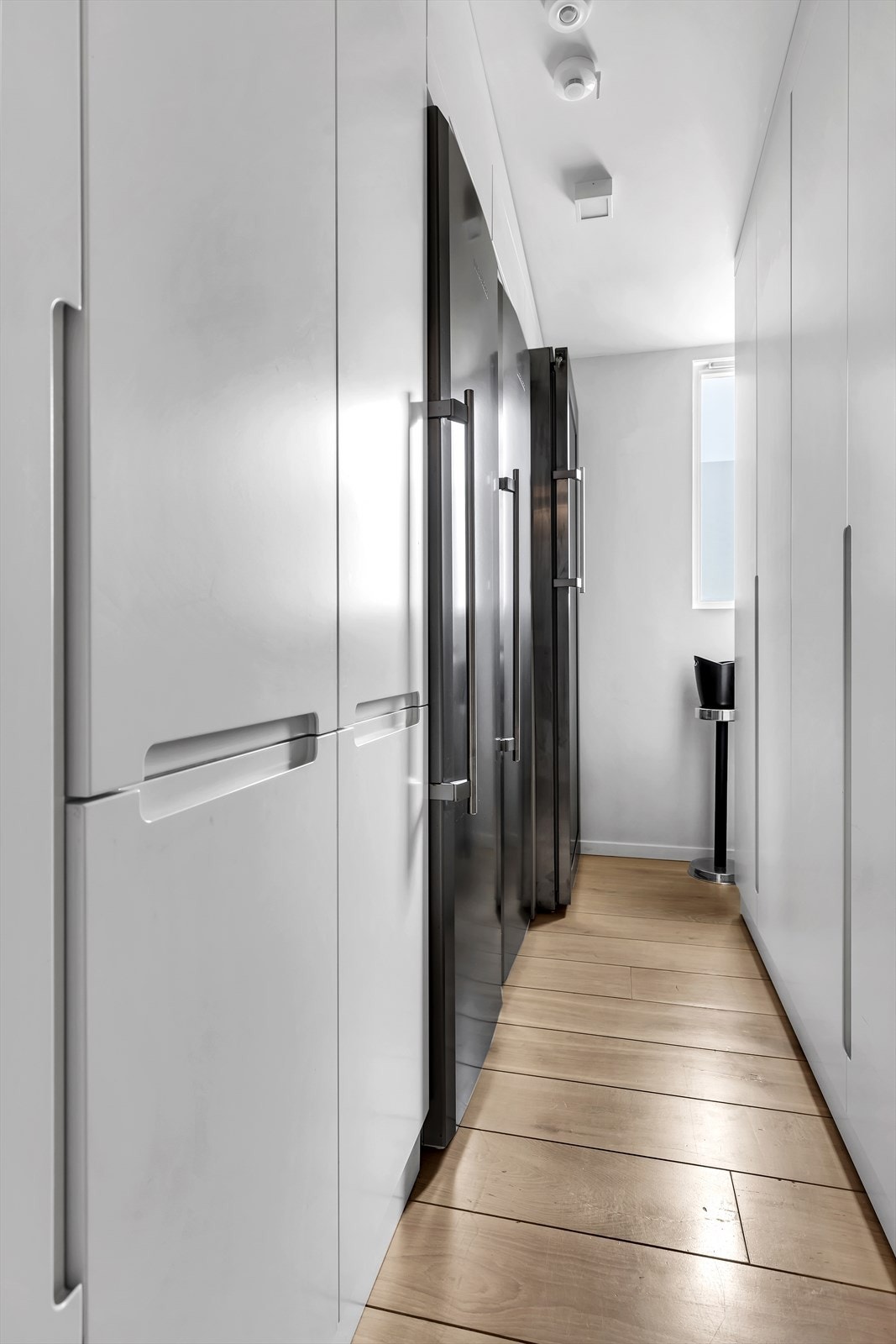 Leiligheten har en praktisk bod ved siden av kjøkken med plass til full hløyde kjøleskap, fryser og vinskap. Plassbyggede skap til søppelhåndtering og lagring. Galleribilde