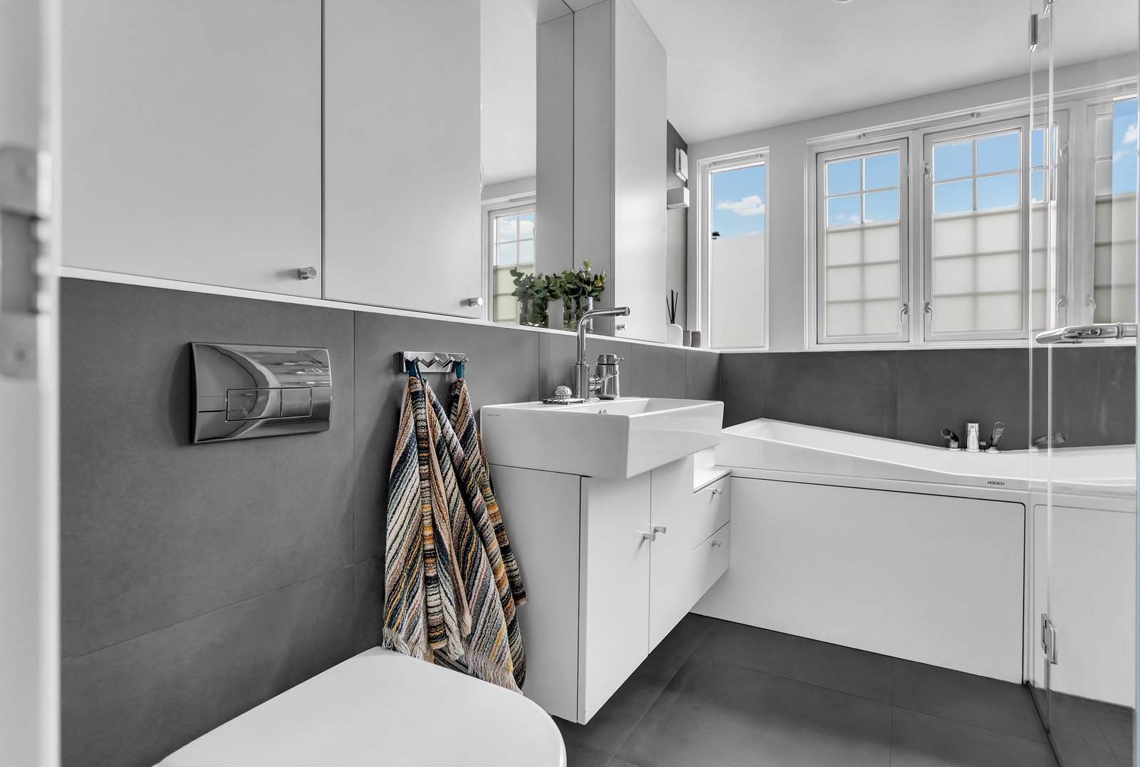 Flislagt pent bad med badekar, godt med skapplass og vegghengt toalett. Galleribilde