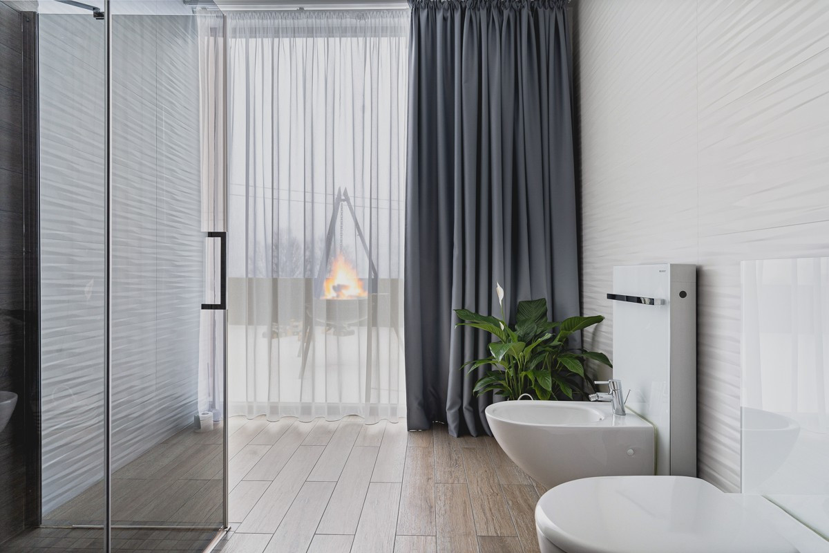 Fra badet er det utsikt mot verandaen utenfor boligen og fjellene i bakgrunnen