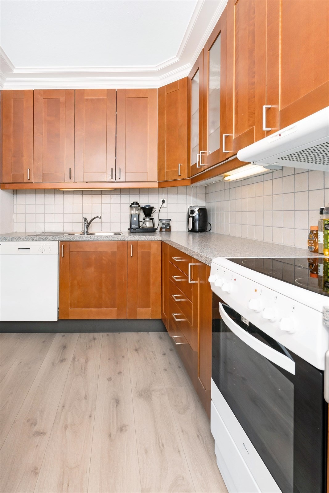 Kjøkkenet inkluderer oppvaskmaskin, kjøleskap og komfyr med platetopp Galleribilde