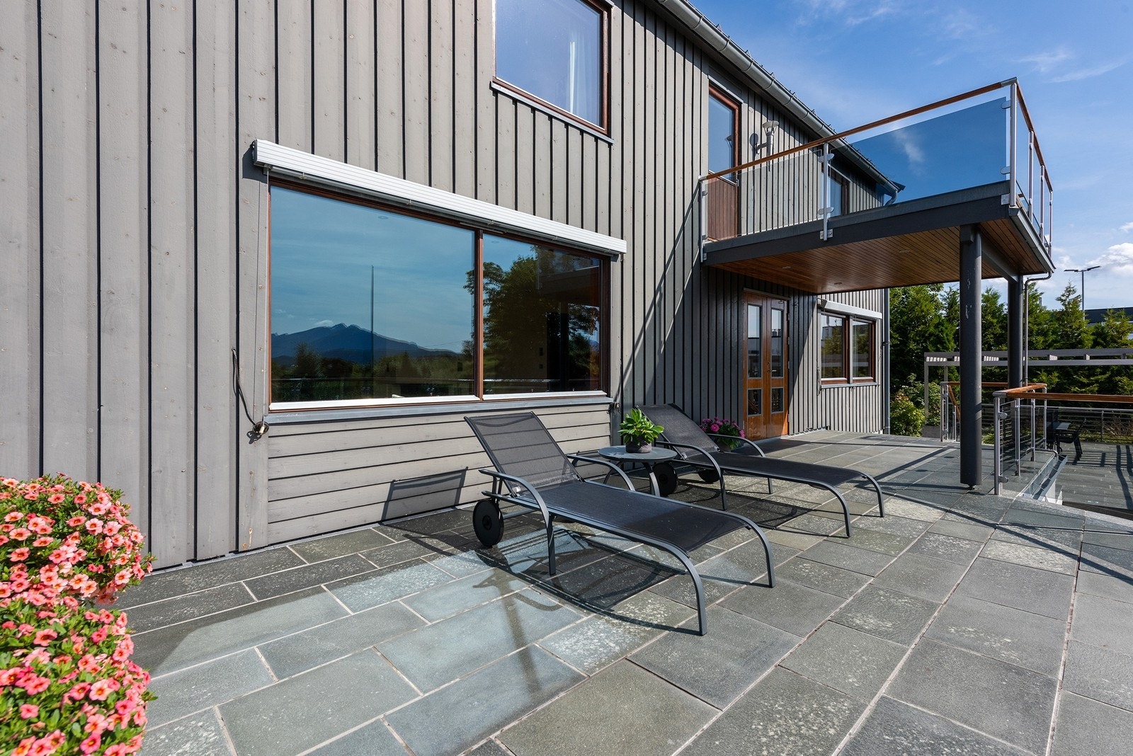 Fra stuen er det dobbel terrassedør til stor skiferbelagt terrasse med store luftige og oppvarmede boder under Galleribilde