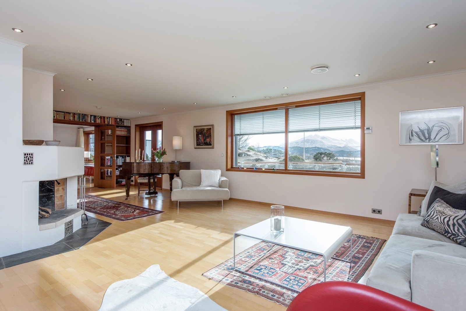 Stue med flott utsikt og bokhyller i teak - store vinduer gir maks belysning og direkte tilgang til stor sydvendt terrasse Galleribilde