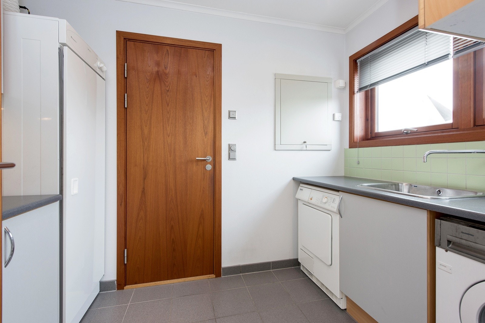 Vaskerom med fliser på gulv, spesialtilpasset innredning fra HTH med Husquarna tørkeskap. Vola blandebatteri Galleribilde