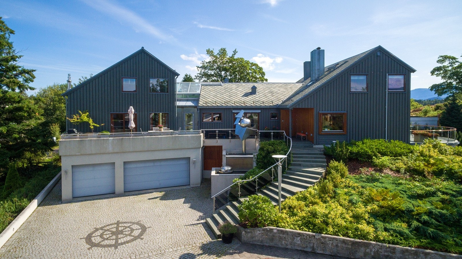 Meget flott opparbeidet eiendom med stor garasje, glassrekkverk og flere uteplasser rundt villa eiendommen Galleribilde