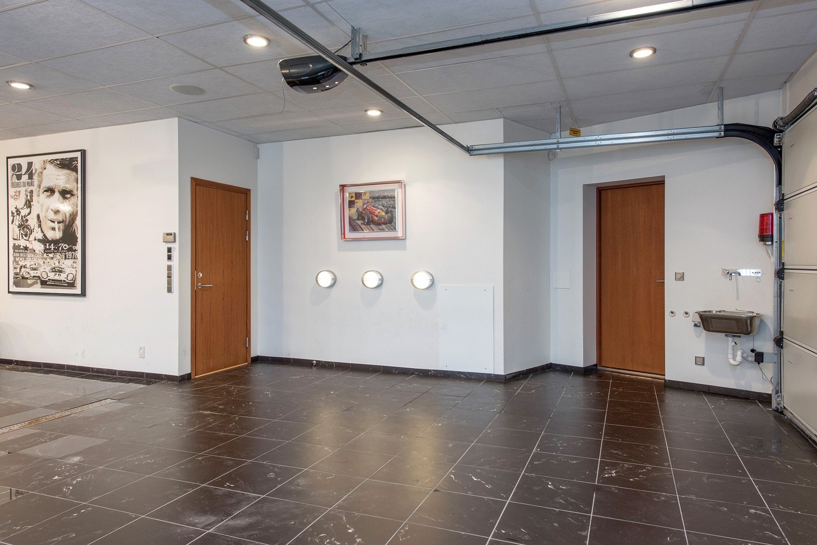 Dør til garasjen, samt to porter. Utslagsvask med Vola blandebatteri og elegant flislagt italiensk marmorgulv . Avansert lyd, lys og bildesetting med projector og elektrisk nedfellbart filmlerret Galleribilde