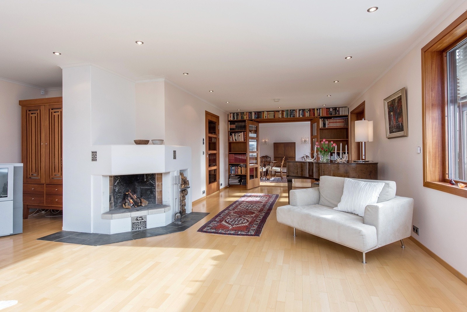 Stor, åpen og luftig stue med elegant peis i funkisstil med tilgang til terrasse mot syd Galleribilde