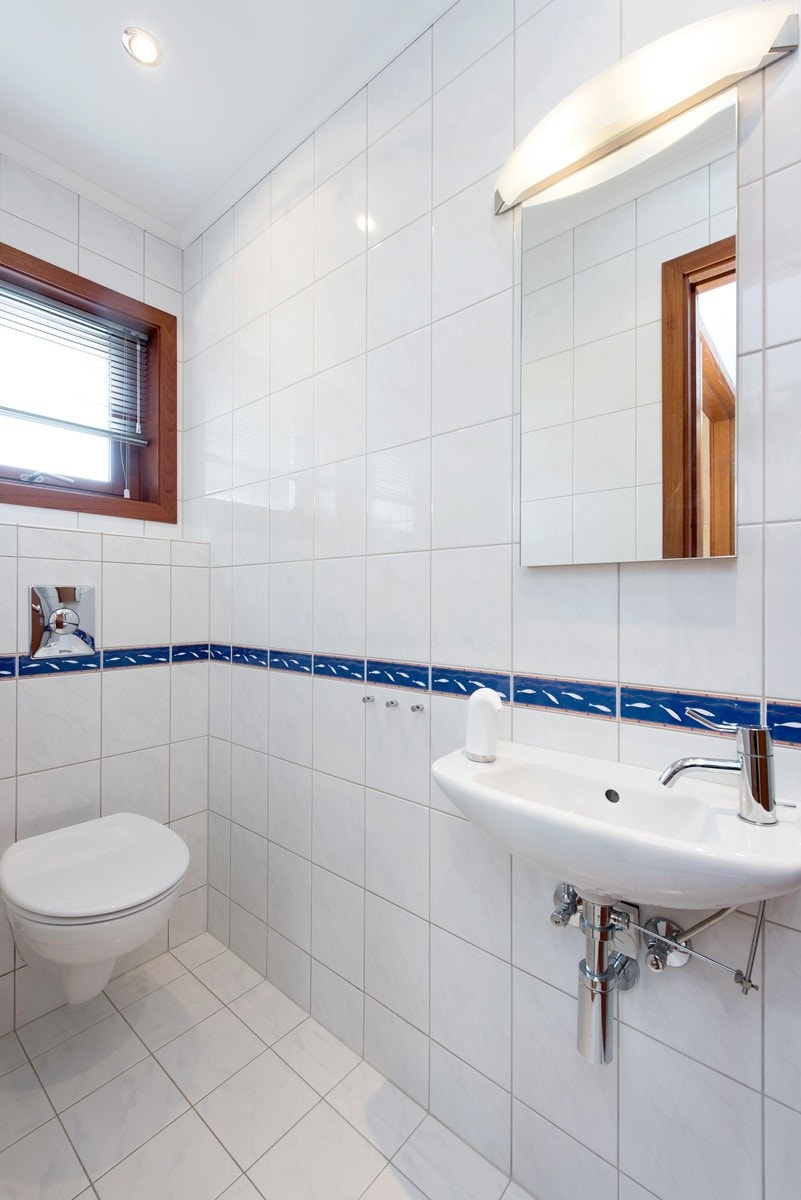 Smakfullt og innbydende flislagt gjestetoalett med Villeroy & Boch og Vola sanitærutstyr Galleribilde