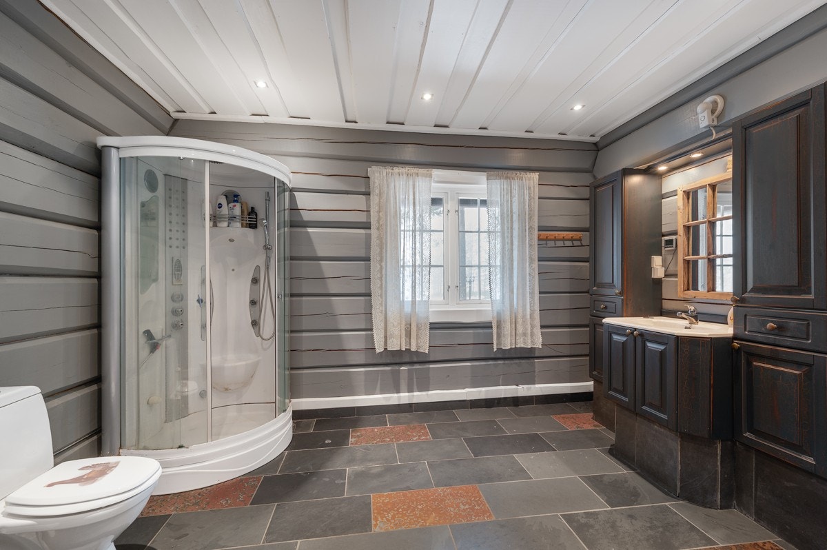Badet er flott med skiferfliser på gulvet og vegger i laftet tømmer. Det er gulvvarme og downlights i himlingen. Galleribilde
