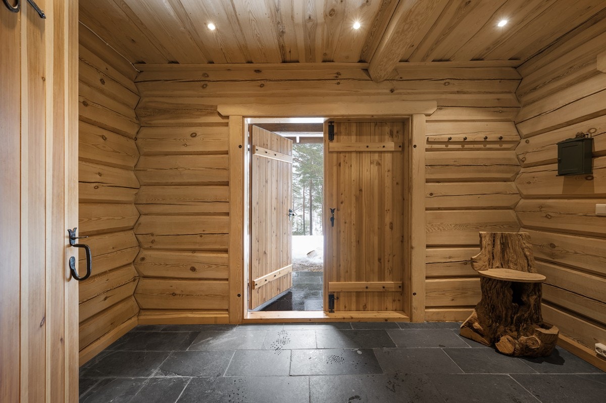 Entreen og gangen er innbydende med grå skiferfliser på gulvet og med vegger i laftet tømmer. Galleribilde