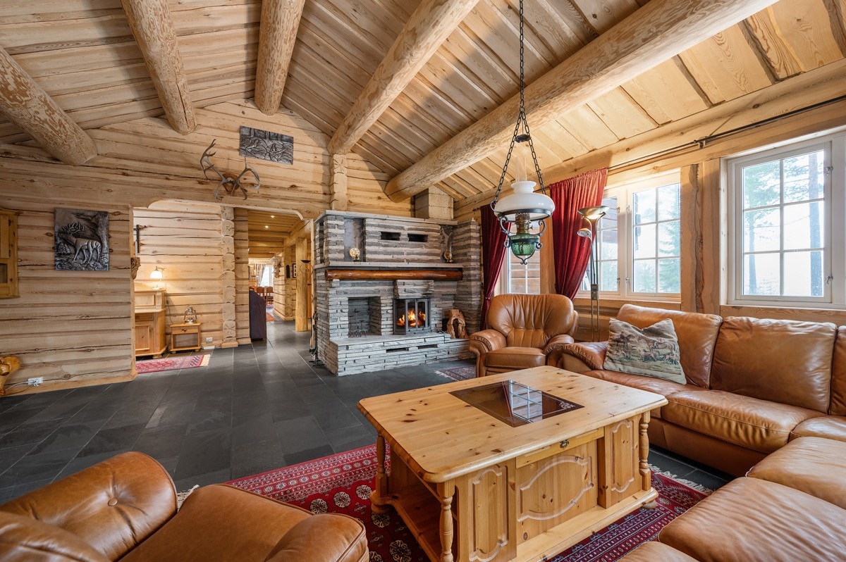Videre har stuen grå skiferfliser på gulvet, vegger i laftet tømmer og åpen himling med store, synlige tømmeråser. Galleribilde