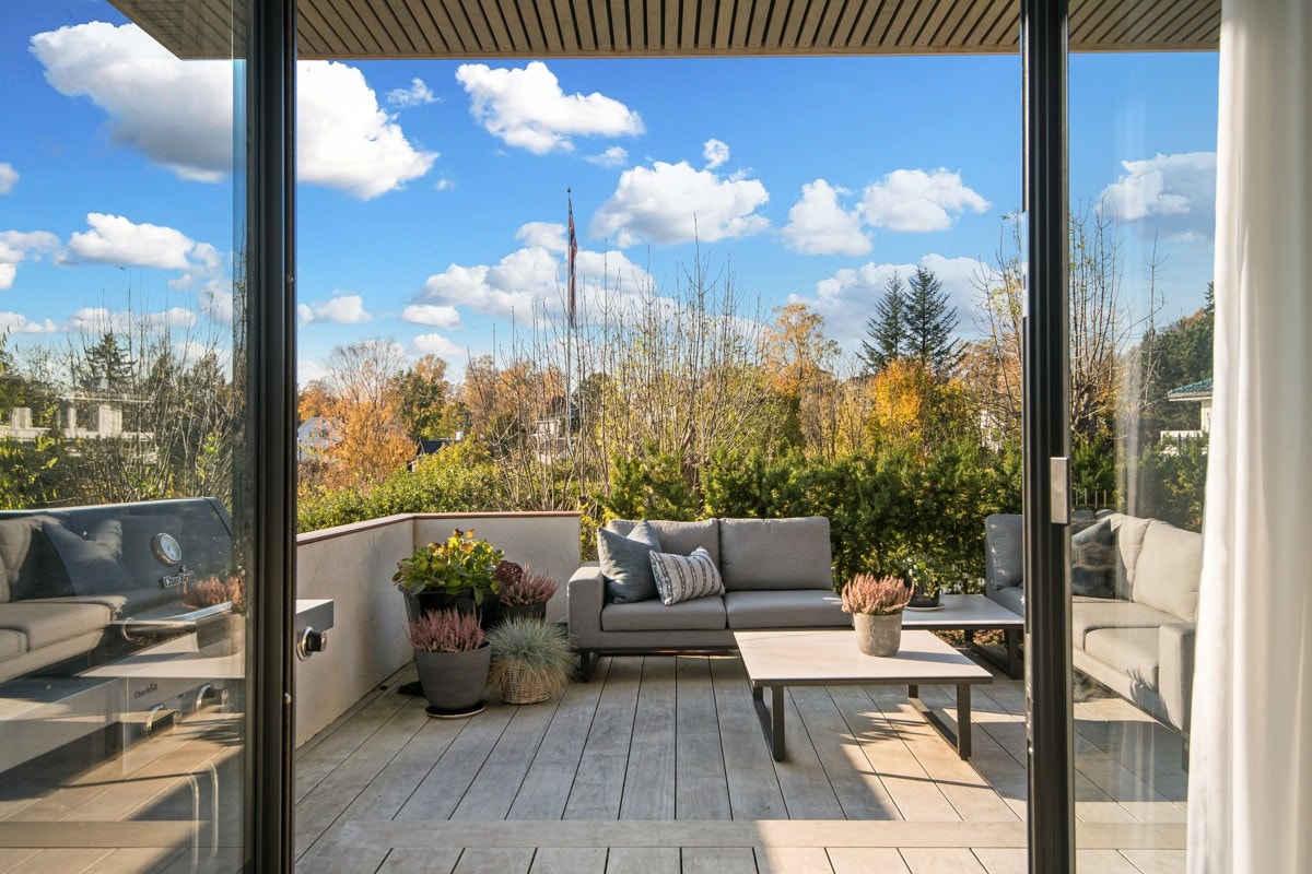 Stor skyvedør i glass fra stue og ut til en solrik terrasse med flott utsyn. Galleribilde