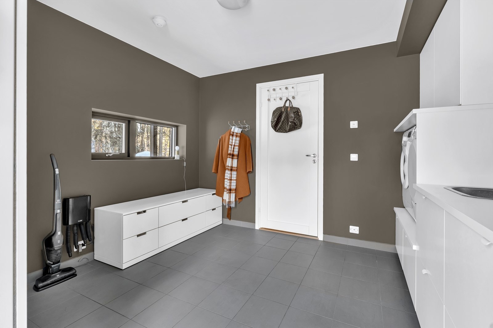 Her har du et helt eget og romslig vaskerom, med fliser på gulvet og rikelig med oppbevaringsløsninger. Galleribilde