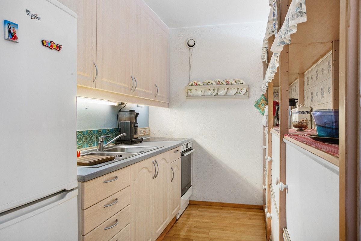 Praktisk kjøkken i delvis åpen løsning mot stuen. Avdelt med fastmontert hylleseksjon mot stue. Galleribilde