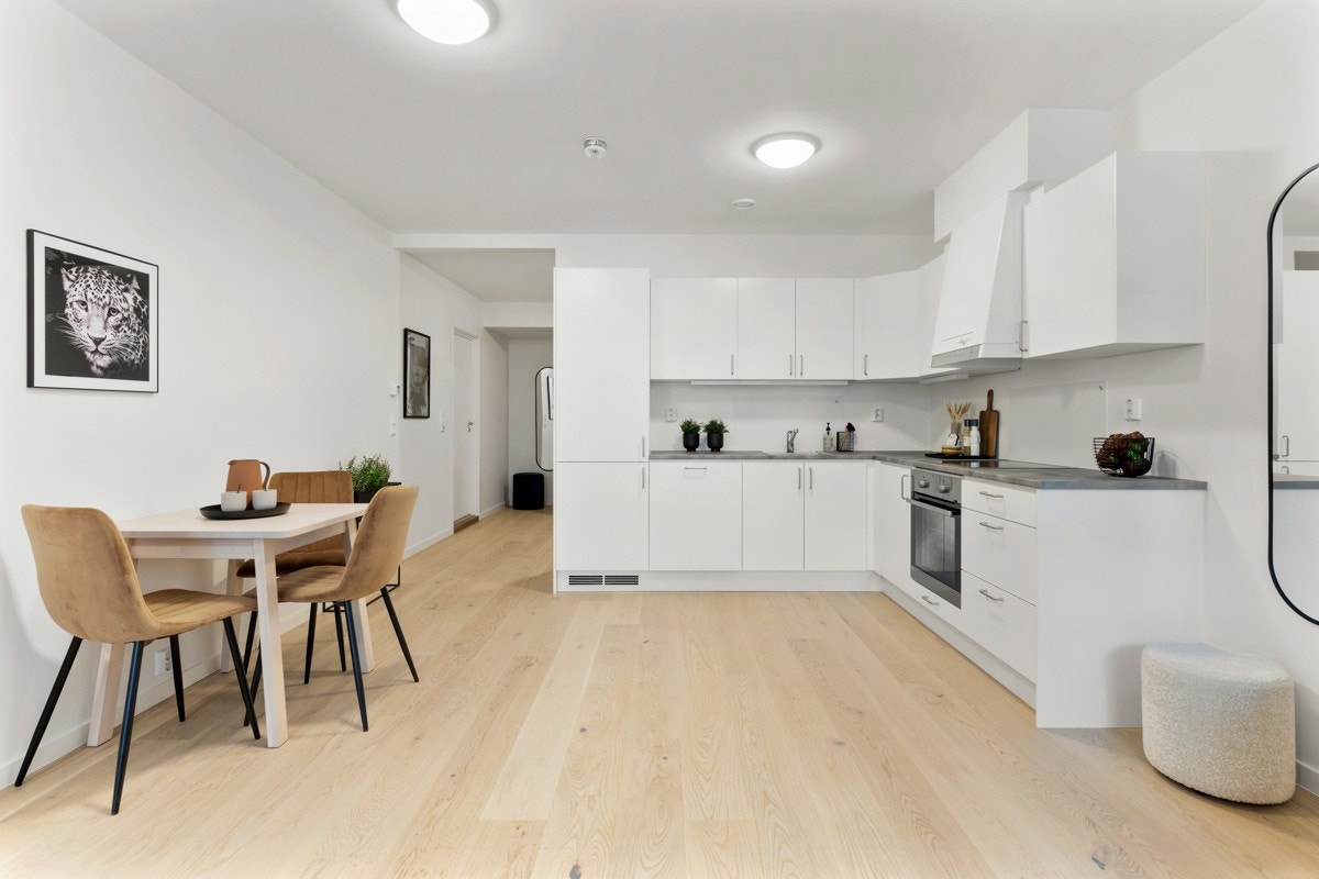 Kjøkkenet i leiligheten har godt med lagringsplass i over- og underskap samt plass til spisebord. Galleribilde
