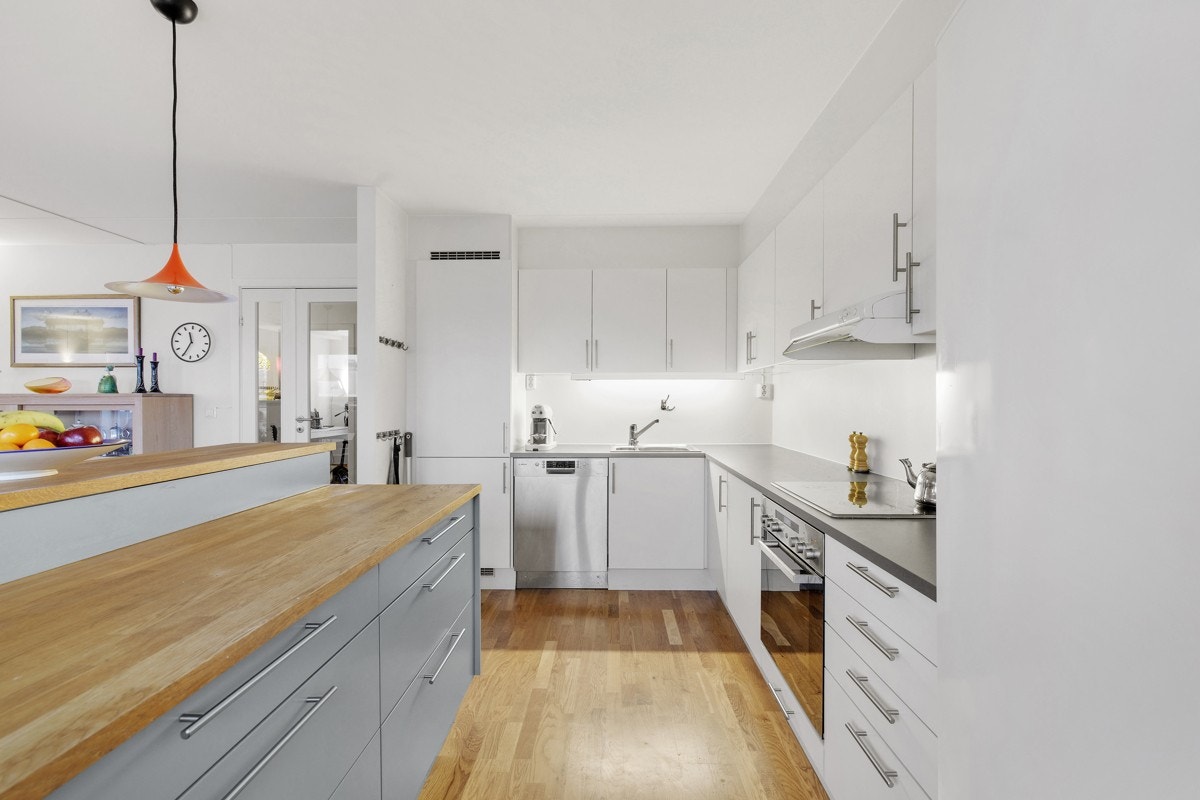 Stilren og moderne kjøkkeninnredning i åpen løsning mot stuen Galleribilde