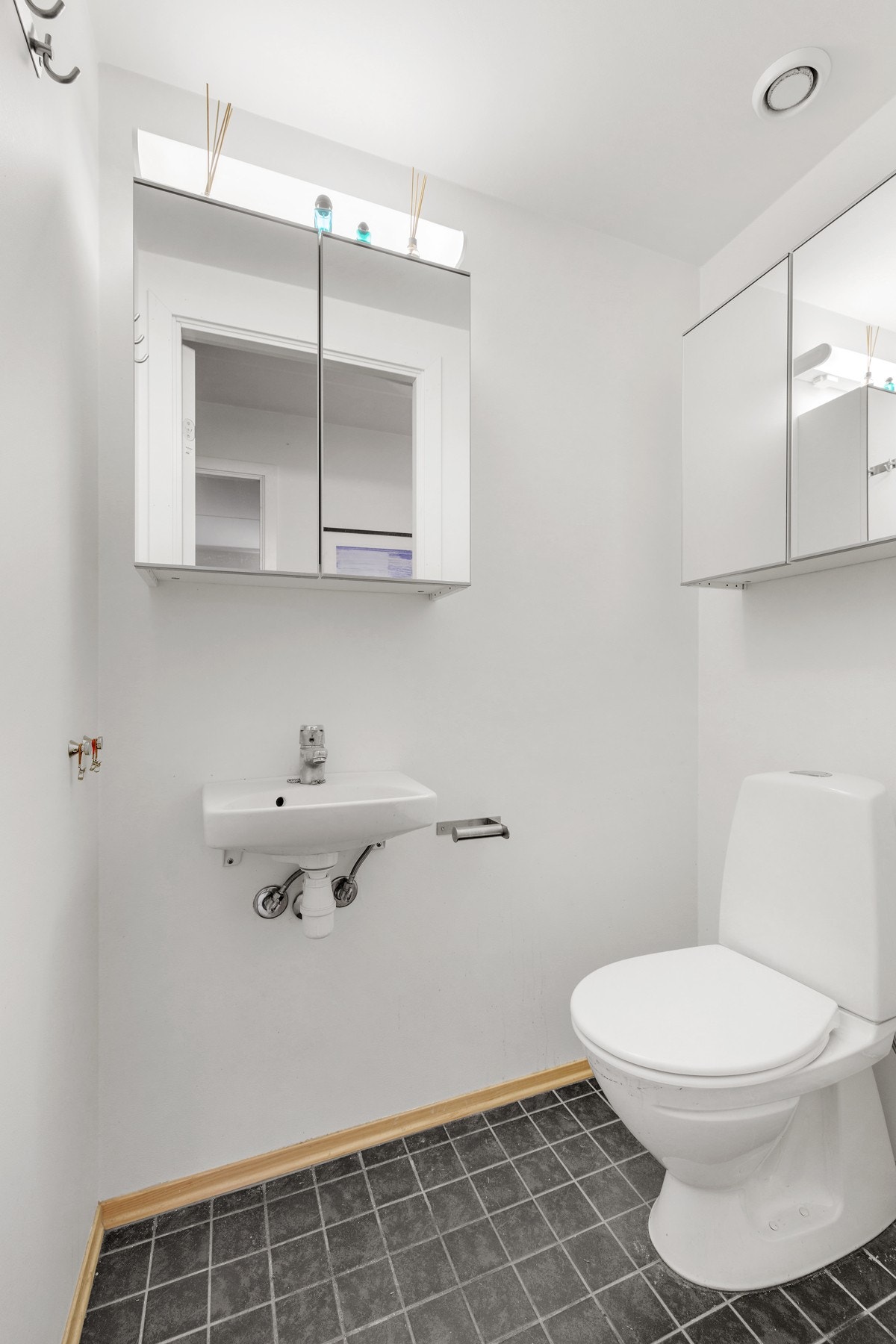 Med adkomst fra entréen har leiligheten et separat wc med flislagt gulv og malte veggflater. Vegghengt toalett med utenpåliggende sisterne og servant på vegghengt servantskap. Galleribilde