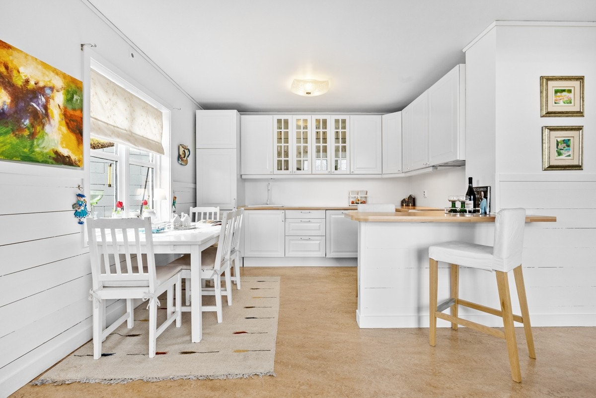 Kjøkken / stue i åpen løsning med dør ut på sørvendt terrasse - kjøkkenet har en romslig innredning med kjøkkenøy og plass til spisebord Galleribilde