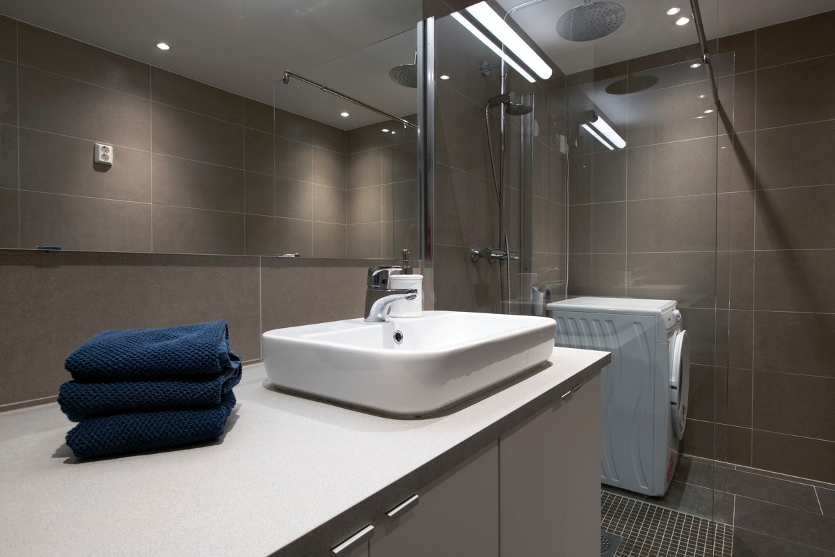 Det stilfulle badet har grå gulvfliser og delikate veggfliser. Galleribilde