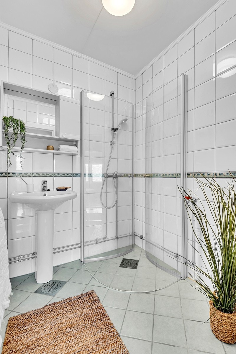 Badet er utstyrt med servant, speilskap, dusj med dusjvegger i herdet glass og håndkletørker. Galleribilde