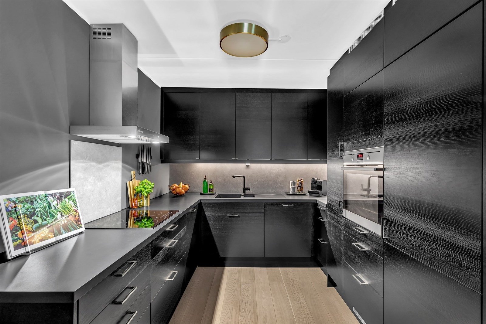 Kjøkkeninnredningen har mørke fronter og håndtak av stål. Galleribilde