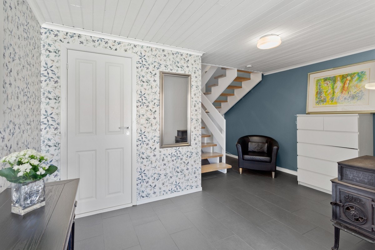 Gangen har grå fliser på gulvet kombinert med dekortapet. Vedovnen i gangen gir god varme til hele boligen. Fra gangen er det tilkomst til et modernisert baderom. Galleribilde
