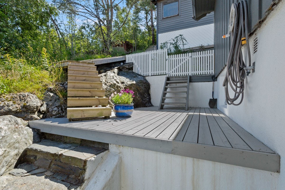 Område langs huset der vaskerommet og soverommet har egen inngang. Her er det terrassebord, nytt steindekke og trapper opp til uteboden. Uteboden er et genialt treningsrom. Galleribilde
