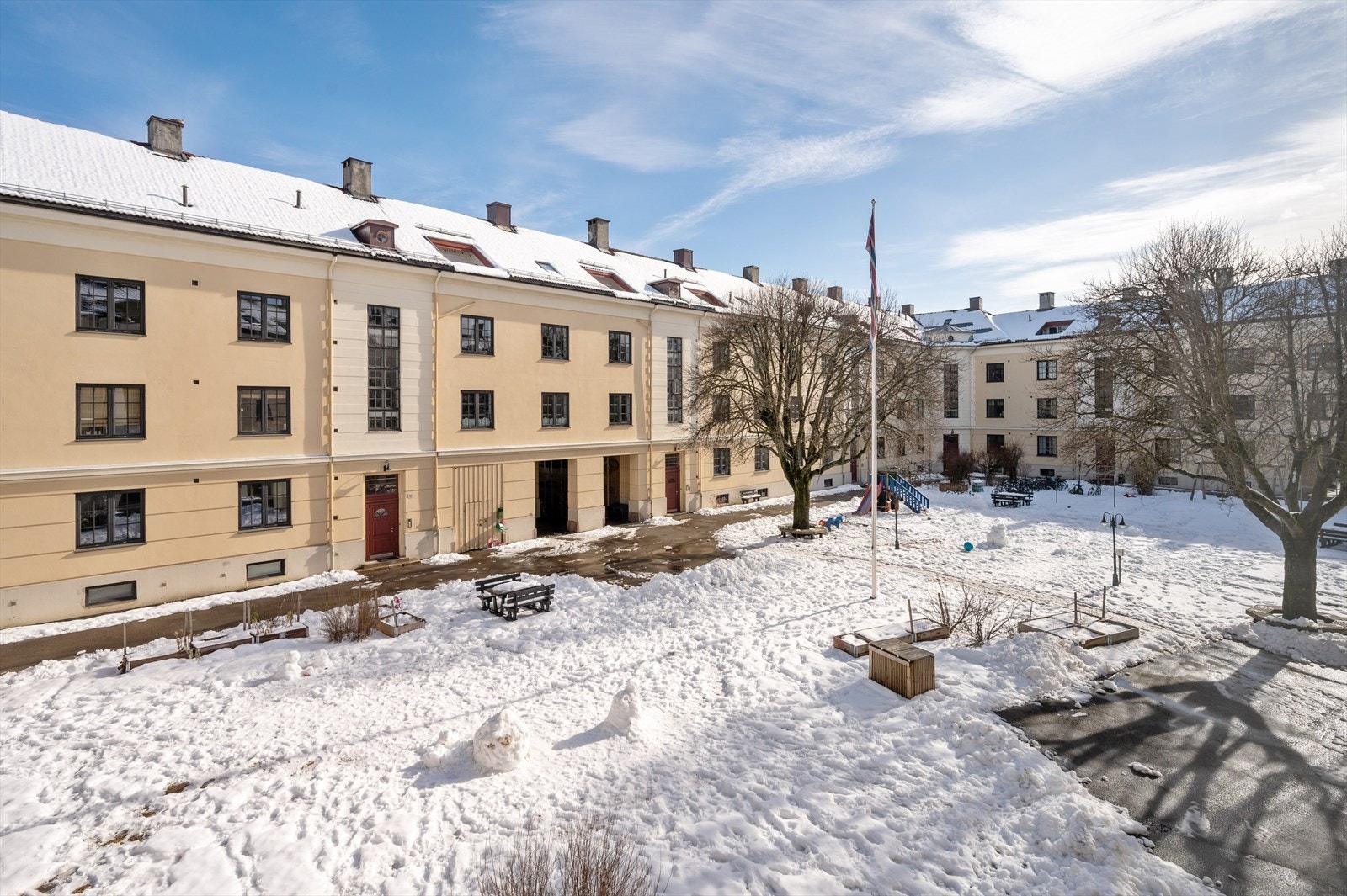 Pent opparbeidet og idyllisk bakgård med solinnfall, steinbelagte arealer, gressplen, beplantning, trær, lekeapparater, sittegrupper m.m. Galleribilde