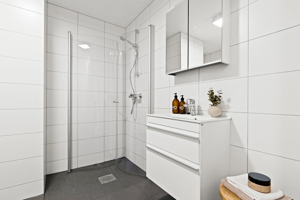 Fint bad med lyse overflater, varmekabler i gulvet og plass til oppbevaring av baderomsartikler. Galleribilde