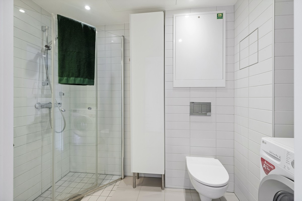 Innbydende bad med dusj, wc, innredning og plass til vaskemaskin Galleribilde