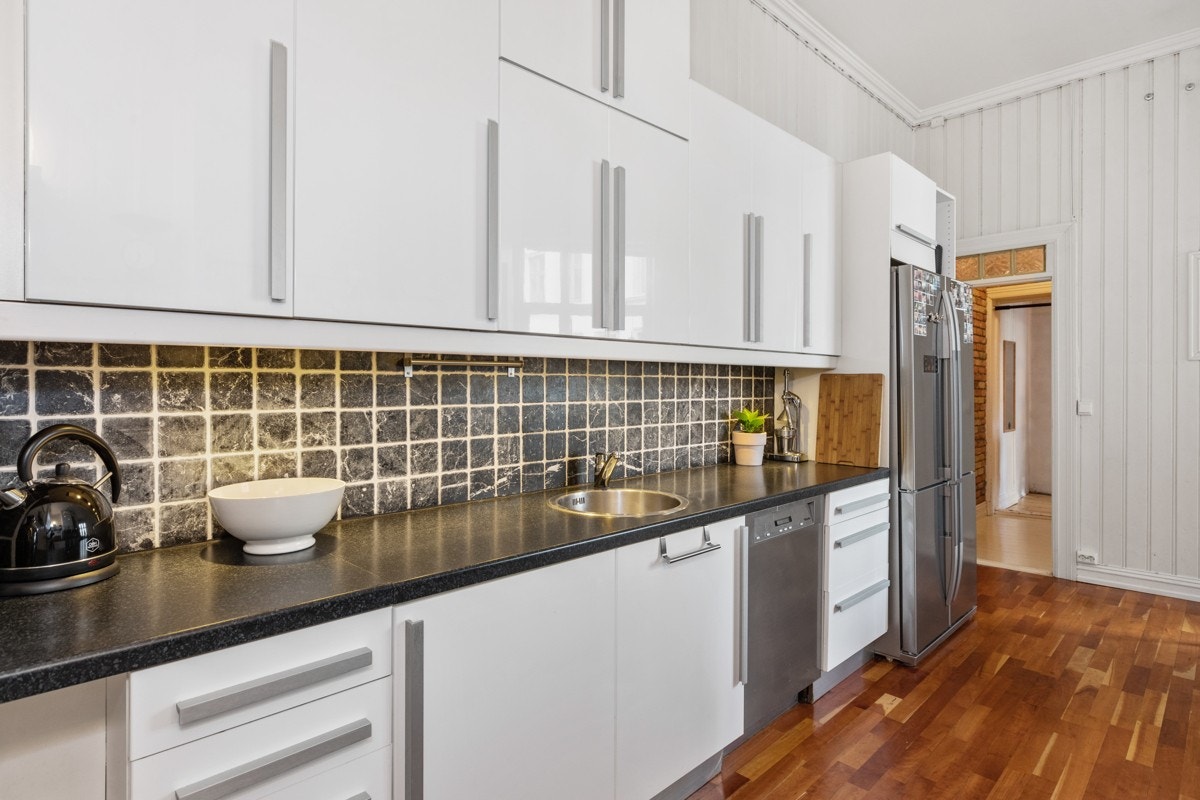 Kjøkkeninnredningen består av glatte fronter, laminat benkeplate, oppvaskkum, ventilator med komfyrvakt, samt opplegg for oppvaskmaskin. Galleribilde