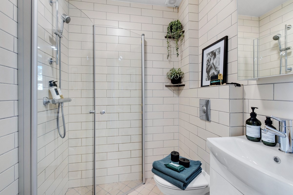 Det er lagt fliser på gulv og vegger. Vegghengt toalett med innebygd sisterne. Servant (2021) på gulvstående servantskap (2021). Det er opplegg til vaskemaskin på badet. Galleribilde