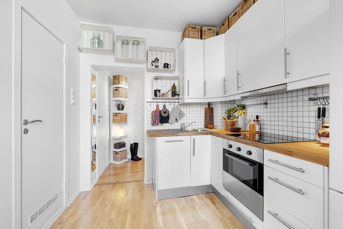 Fronter i høyglans utførelse. Heltre benkeplate med innfelt kjøkkenvask. Flislagt vegg over kjøkkenbenk. Opplegg for frittstående kjøl/frys (2017). Integrert komfyr, platetopp og oppvaskmaskin. Galleribilde